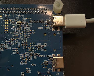Image Alt Text:Close-up of the Alif Ensemble E8 DevKit showing a USB-C cable connected to the PRG USB port; the separate MCU USB port is visible below