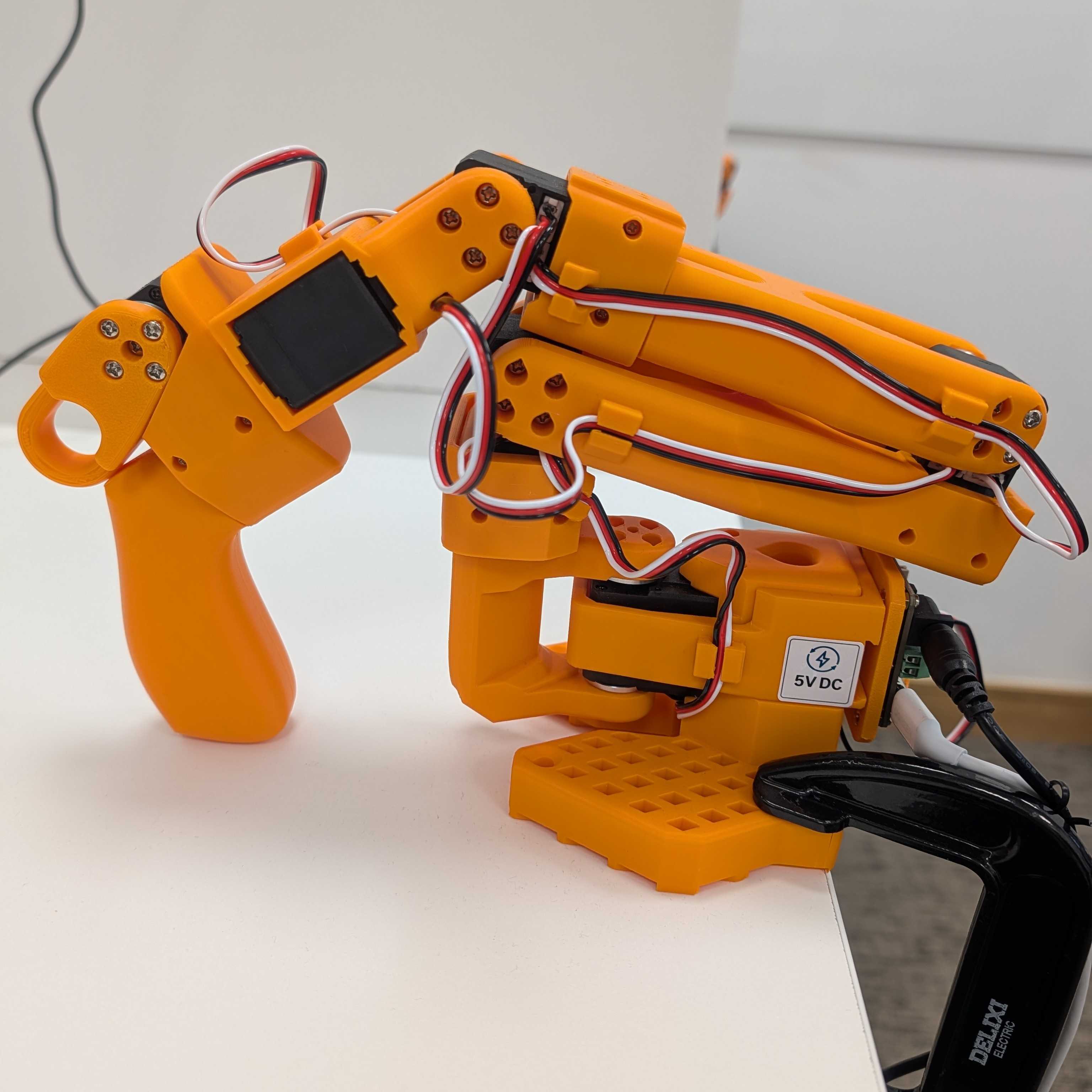 SO-101 leader arm Image Alt Text:SO-101 leader arm with the operator handle used to demonstrate joint and gripper movements. The leader sends target positions to the follower during teleoperation and data collection.