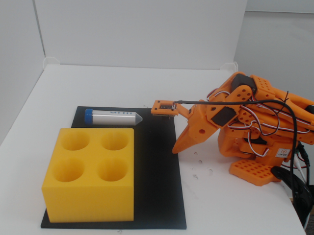 Workspace camera view Image Alt Text:LeRobot camera-discovery frame showing the follower, vial, yellow rack, and full range of arm movement. Use this view for the <code>workspace_cam</code> role.